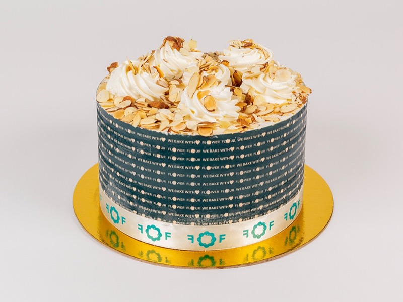 Burnt almond cake with whipped cream rosettes and toasted sliced almonds in a teal Flower Flour band