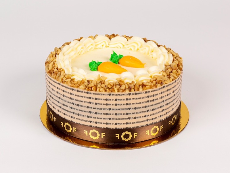 Carrot cake with cream cheese rosettes, chopped walnuts, and piped carrots