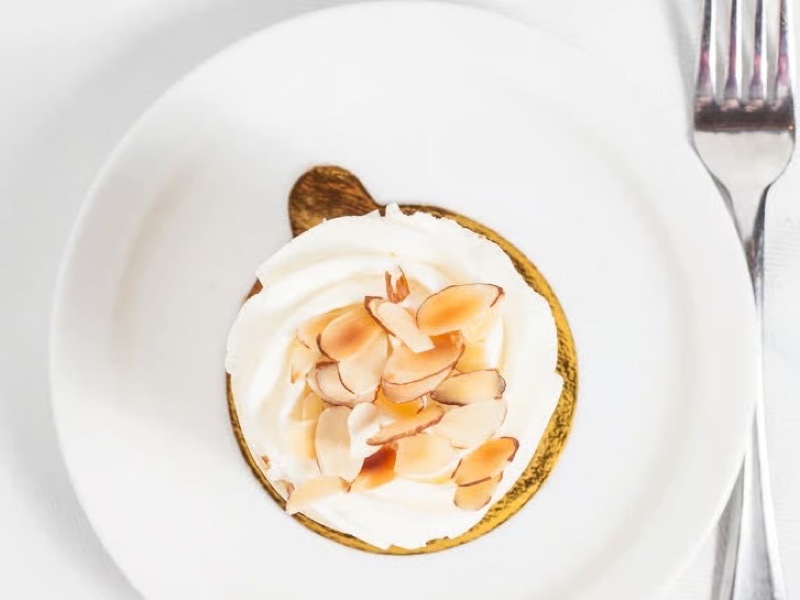 Individual Burnt Almond cake topped with whipped cream and toasted sliced almonds