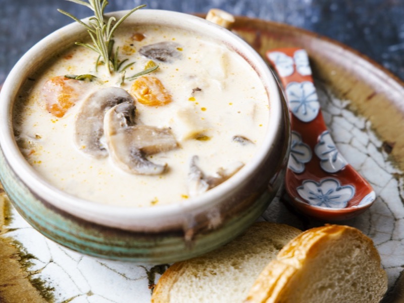 A bowl of creamy soup with bread on the side